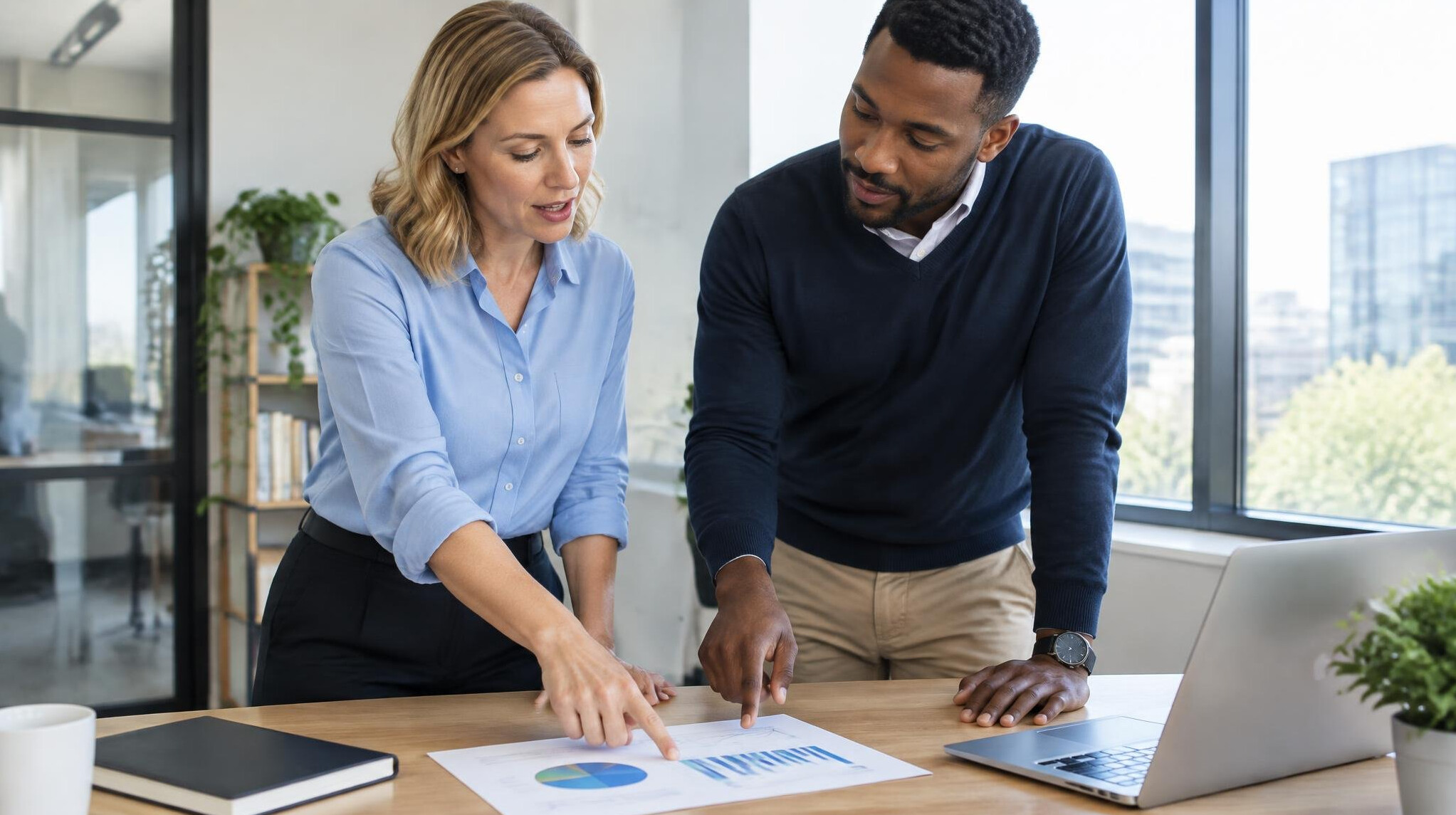 Two colleagues reviewing notes together at a desk