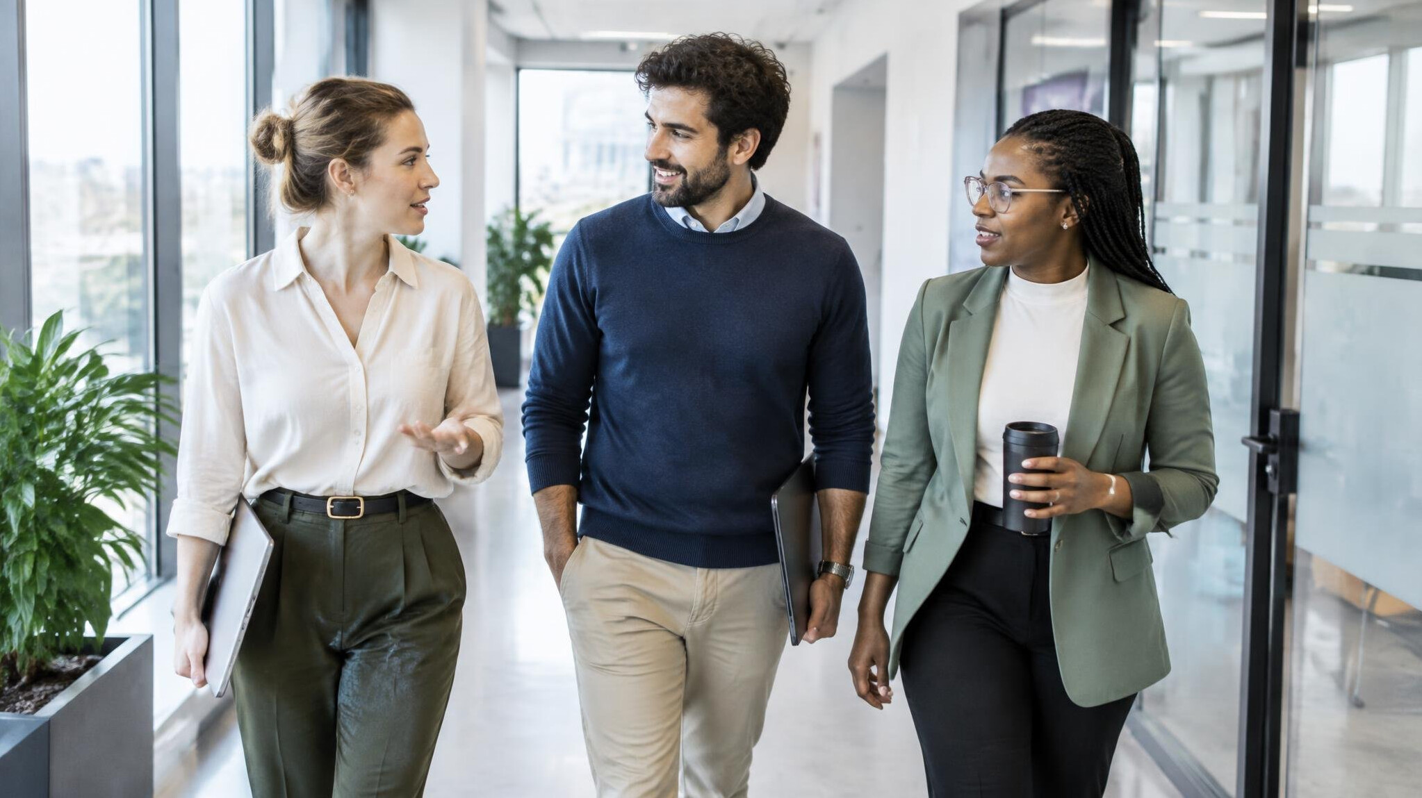 Colleagues walking together down a bright office corridor